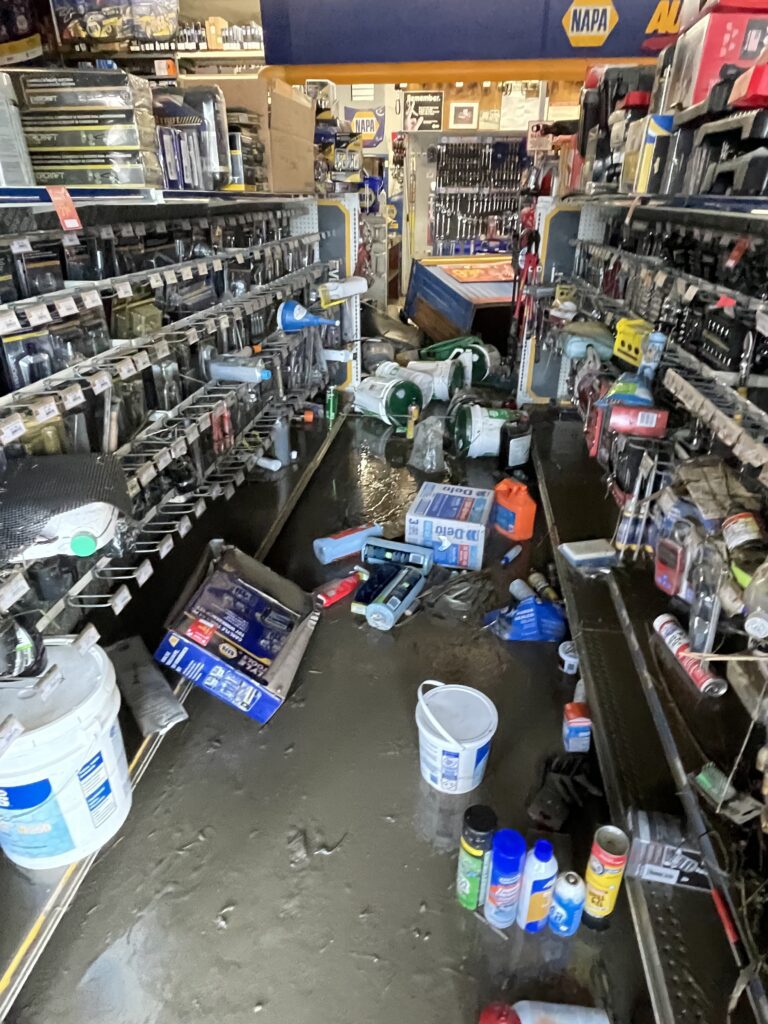 An aisle of store items stewn onto the floor due to the flood.
