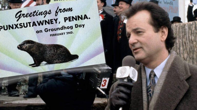 Bill Murray holds a microphone next to a sign that reads "Greetings from Punxsutawney, Penna. on Groundhog Day February 2nd."