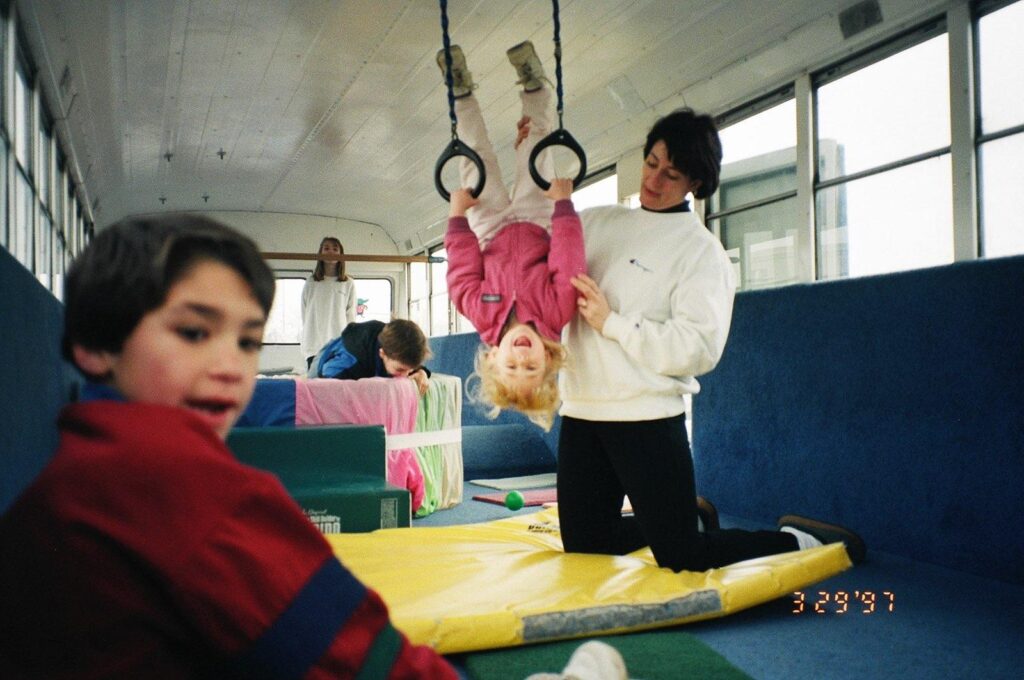 Carolyn helps a young girl on the gymnastics rings on the Gym Bus.