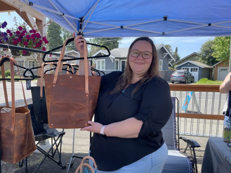 Jenaya Church of Oak Ash Leather Co. holds a signature "Fairhaven tote" at the weekly PNW Made Artisan Market taking place every Sunday at Goods Local Brews on Northwest Avenue in Bellingham. Jenaya's husband and fellow creative