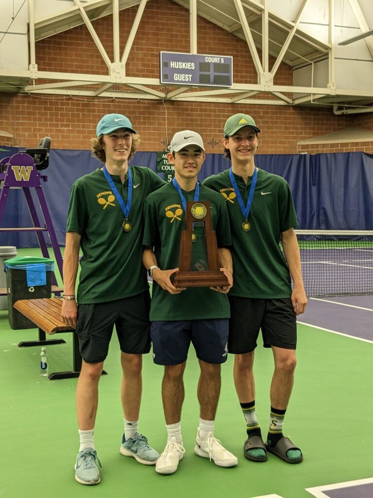 Calvin Kraynak, Zach Chai and Whitt Gresham pose for a photo in the tennis court with the state championship trophy in the middle.