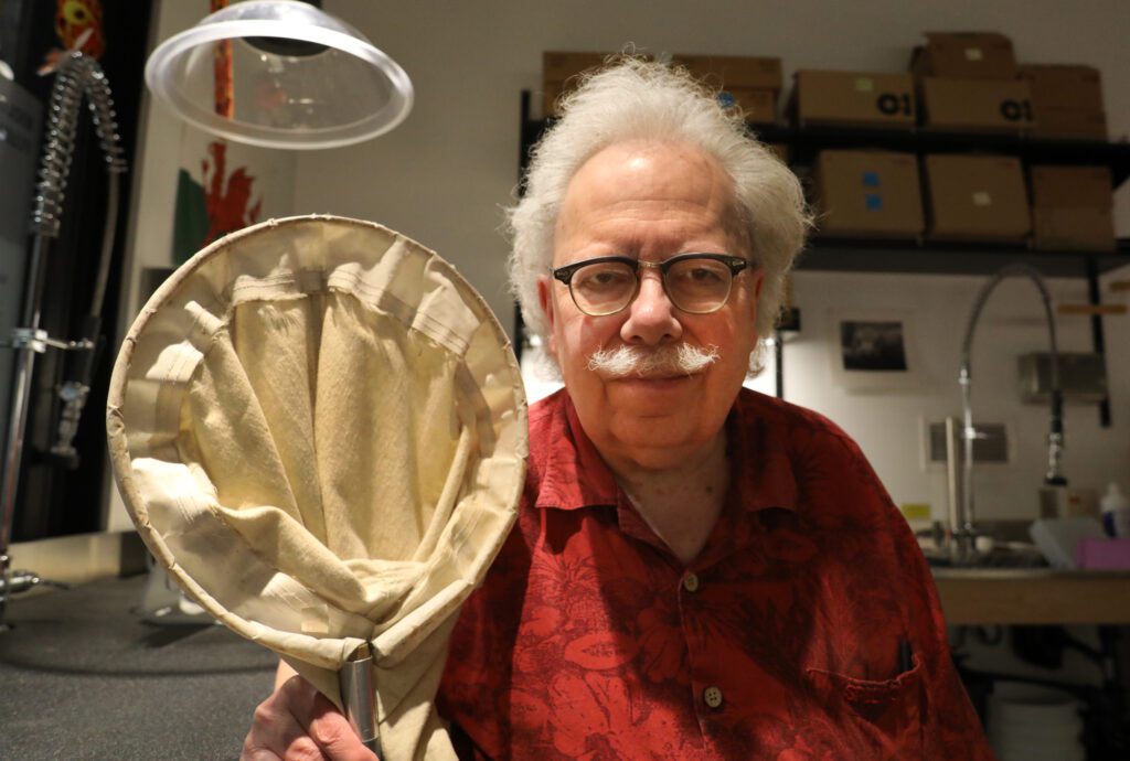 Rod Crawford holds a spider net in his lab.