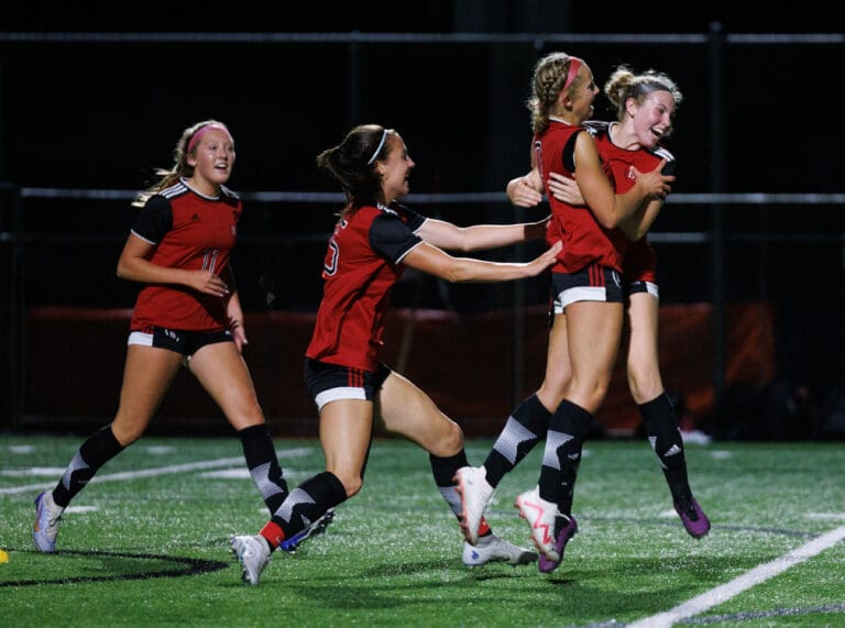 Bellingham’s Ivy Newell celebrates with her teammates as they jump and hug for scoring a goal.