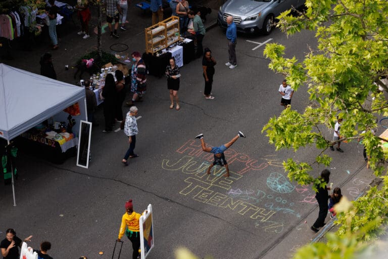 A young boy does a cartwheel over a Juneteenth chalk drawing during the Commercial Street Block Party June 15 in Bellingham.
