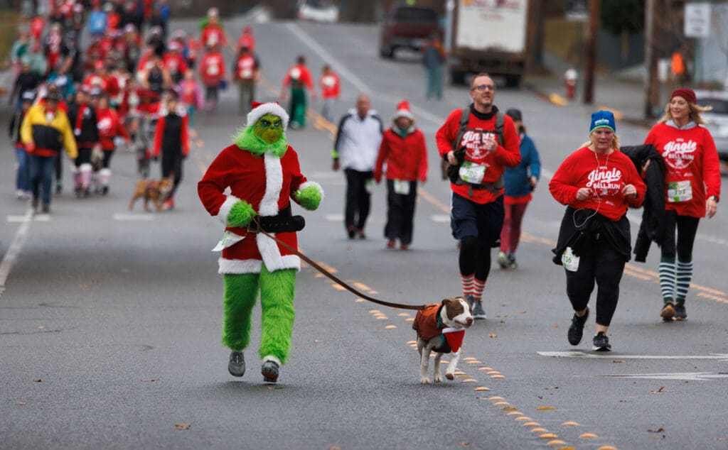 The Grinch runs with Benny to the finish line, leading a crowd of christmas runners.