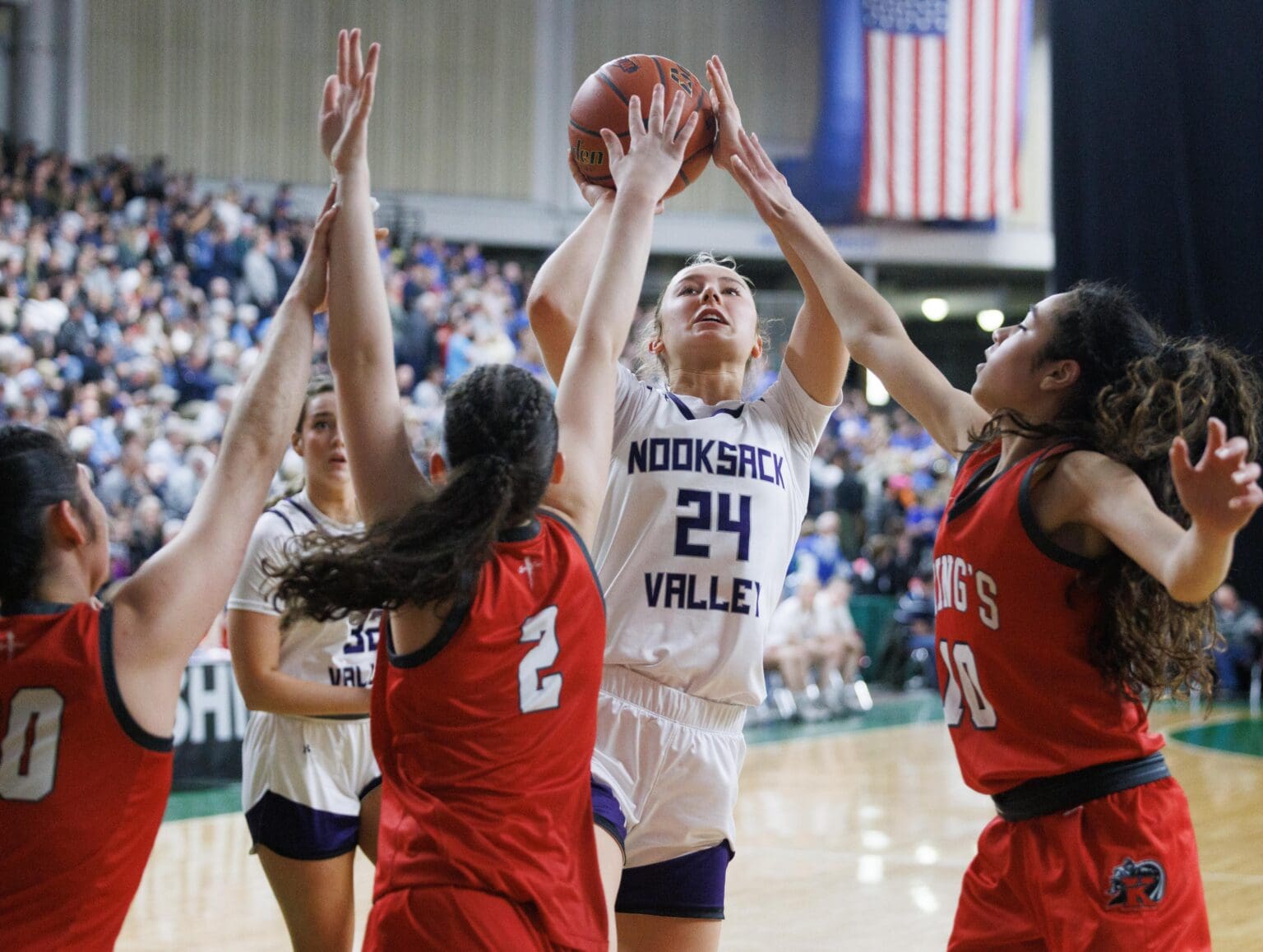 Three King's defenders try to stop a shot by Nooksack Valley's Devin Coppinger as they reach over her with their arms extended.