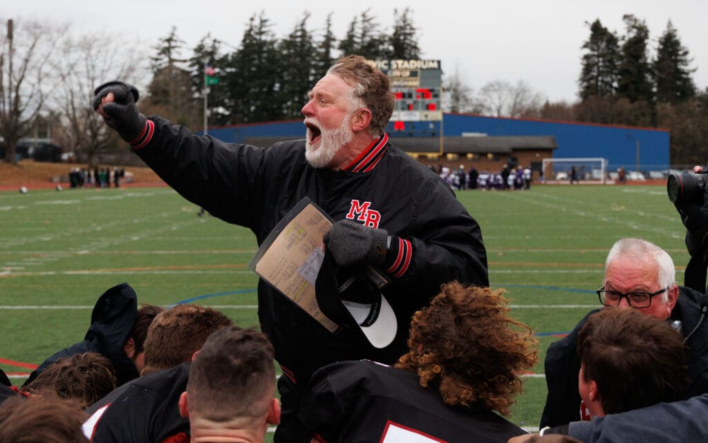 Mount Baker head coach Ron Lepper celebrates the win as he yells in celebration next to his team.