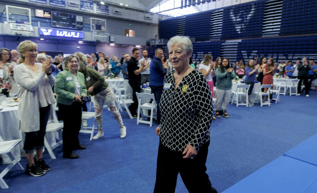 Last in line and walking to a standing ovation, former Western Athletic Direction Lynda Goodrich walks past cheering attendees.