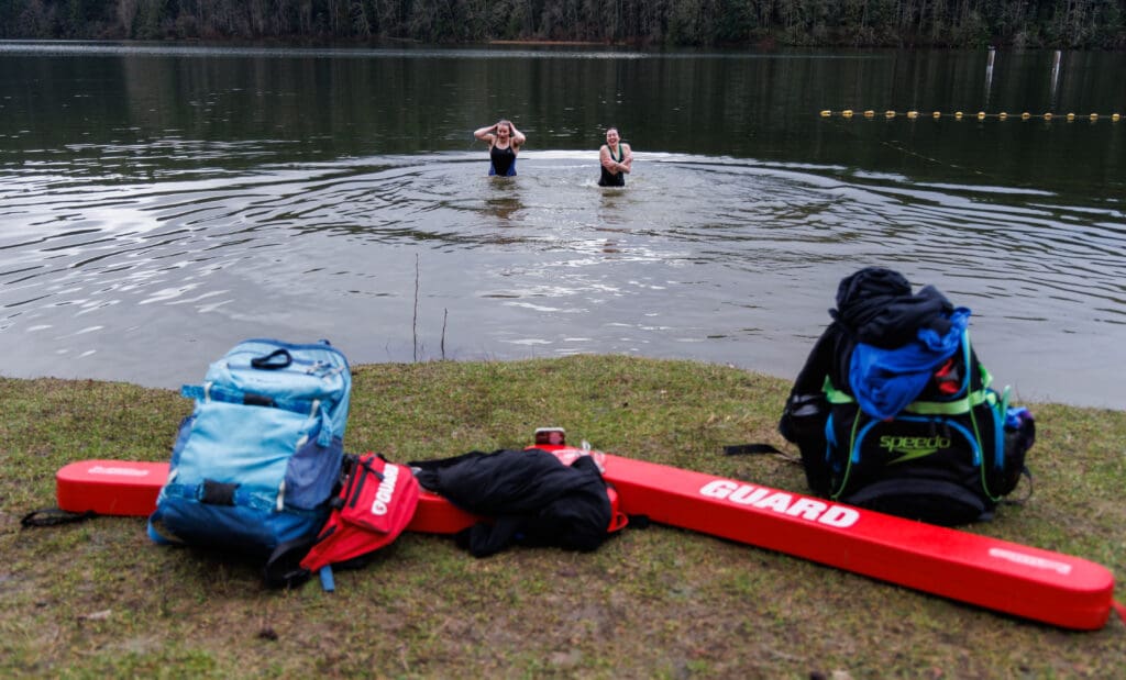 Lifeguards Clara Phundt and Elizabeth Edwards take a dip as their lifeguard gear is left on the grassy.