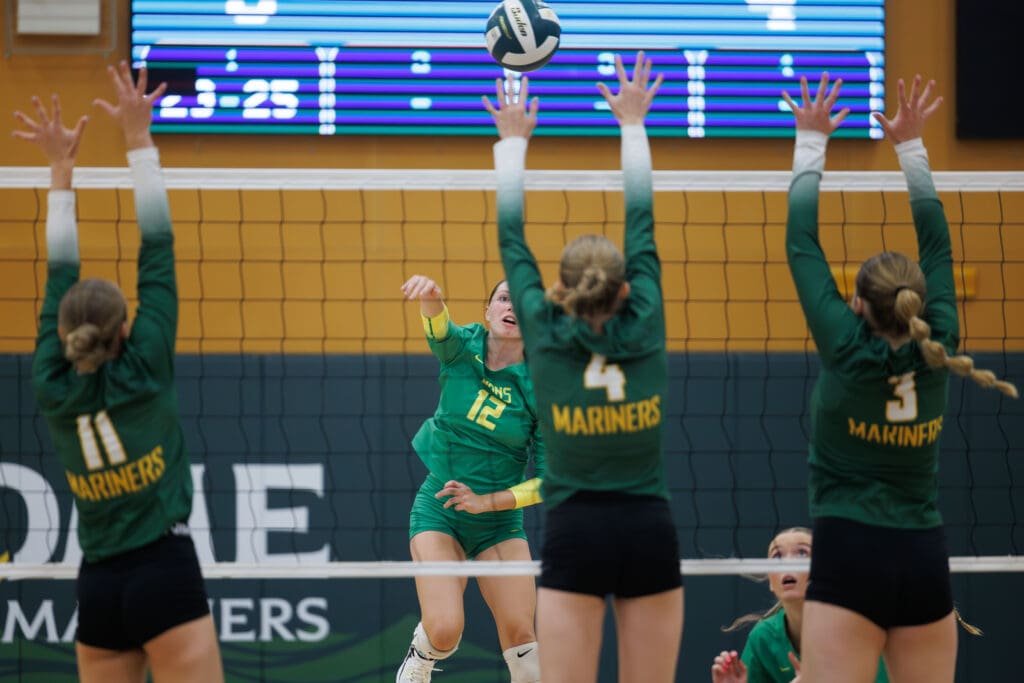 Lynden’s Haylee Koetje hits the ball over the net as three defenders leap to block the shot.