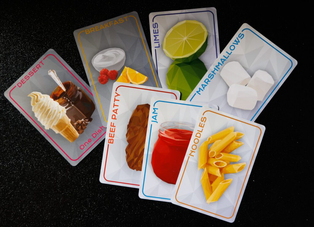Various cards of different types of foods and mealtimes from the boardgame 'Cookdown'.