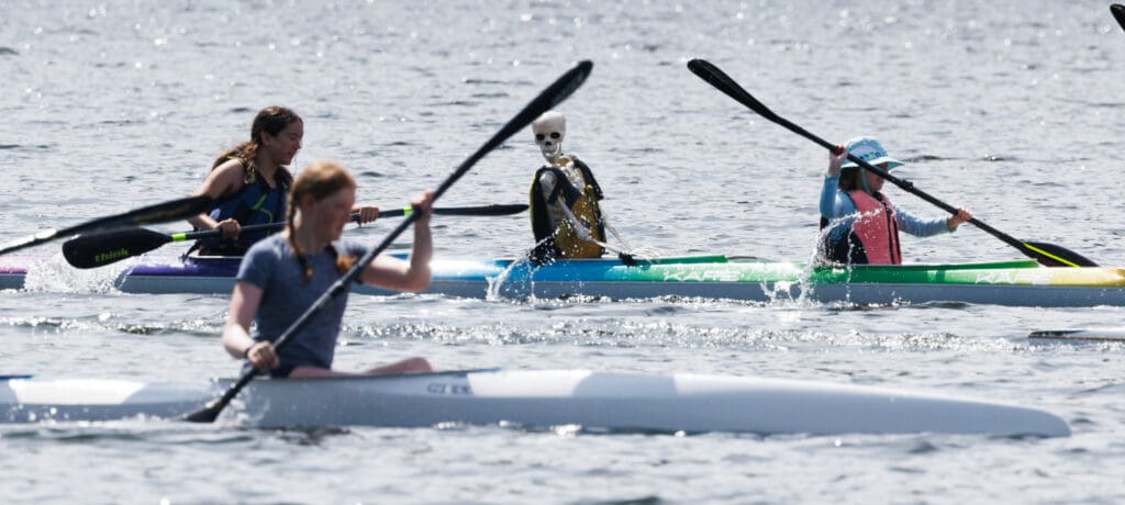 Sully the skeleton appears to be watching as a four-person team is passed by a single rower during practice of the Bellingham Canoe and Kayak Sprint Team on July 2.