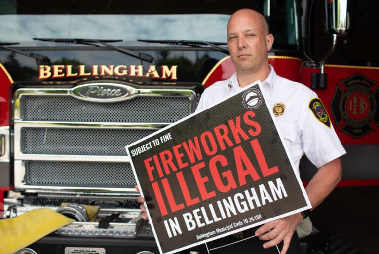 Bellingham Assistant Fire Chief Dave Pethick holds a sign in July 2022 announcing the ban on fireworks in Bellingham.