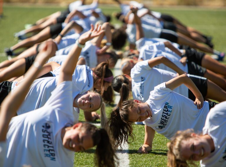 The WWU women's soccer team does side planks during practice on the field.