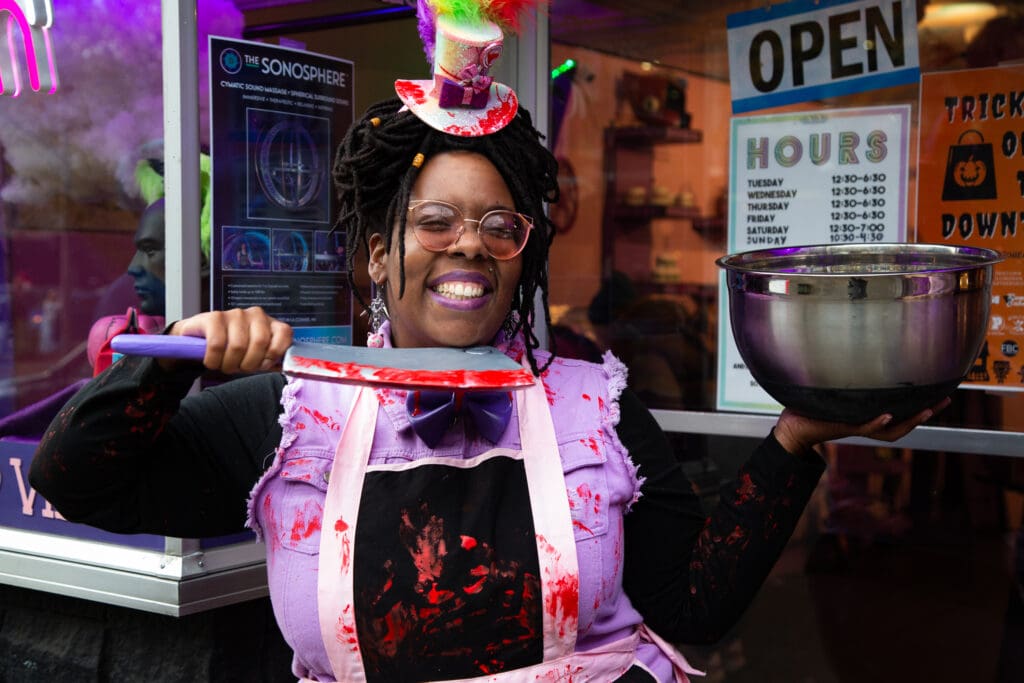 Mo's Parlor owner Mo Green smiles for the camera while holding a bowl and a knife with fake blood on it along with her clothes.