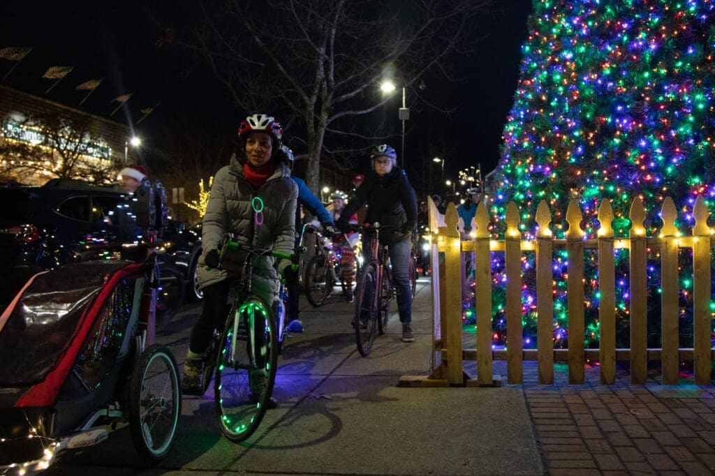 The Lighted Bike Parade attendees begins with a pass by a Christmas tree that is fenced off.