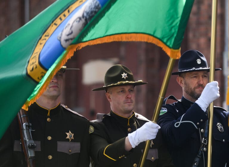 Whatcom County sheriff's deputies and Bellingham police officers carry flags in March at a St. Patrick's Day parade in Bellingham. A new proposal would make the county sheriff's position appointed rather than elected.
