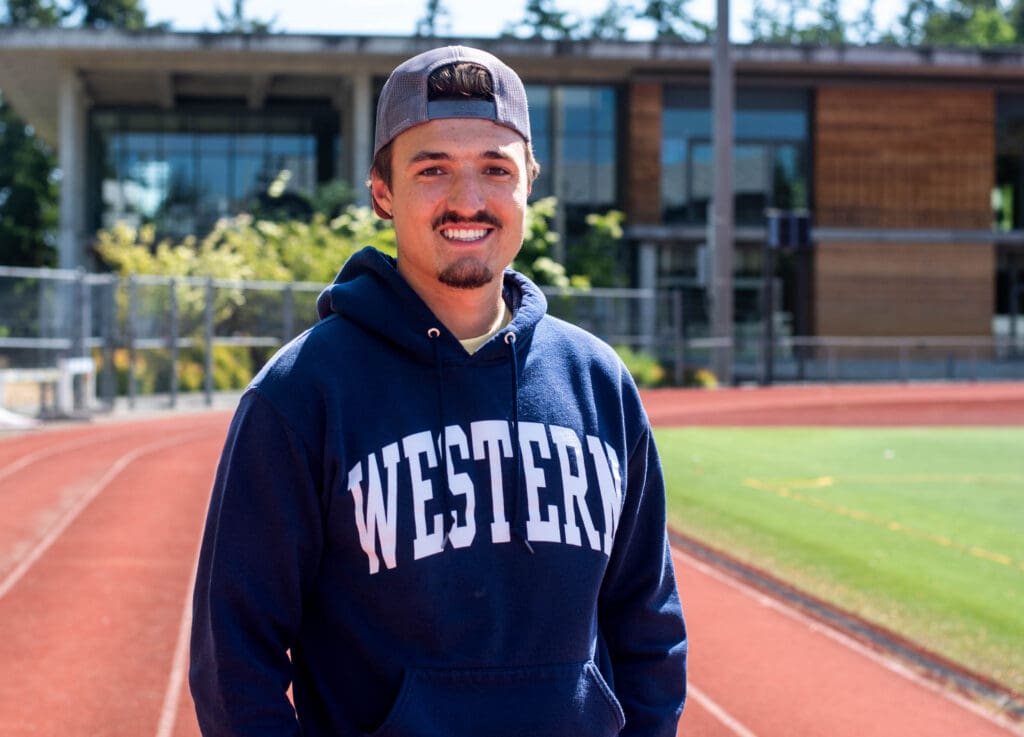 Cooper Cummings stands on the track at Western Washington University. The former Viking decathlon athlete is now a substitute teacher and a coach at Nooksack Valley High School.