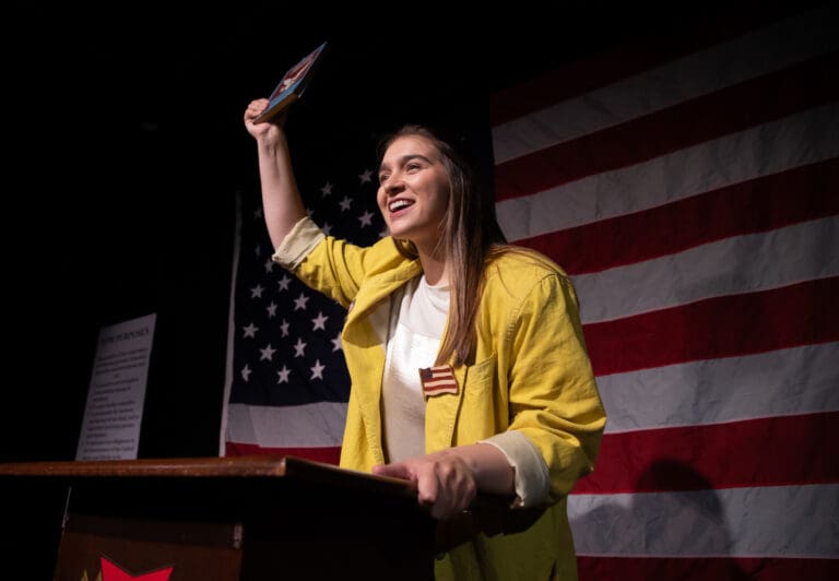 Gabi Gilbride as Heidi Schreck holds a copy of the Rugged Constitution while performing at the FireHouse Arts and Events Center on Sunday