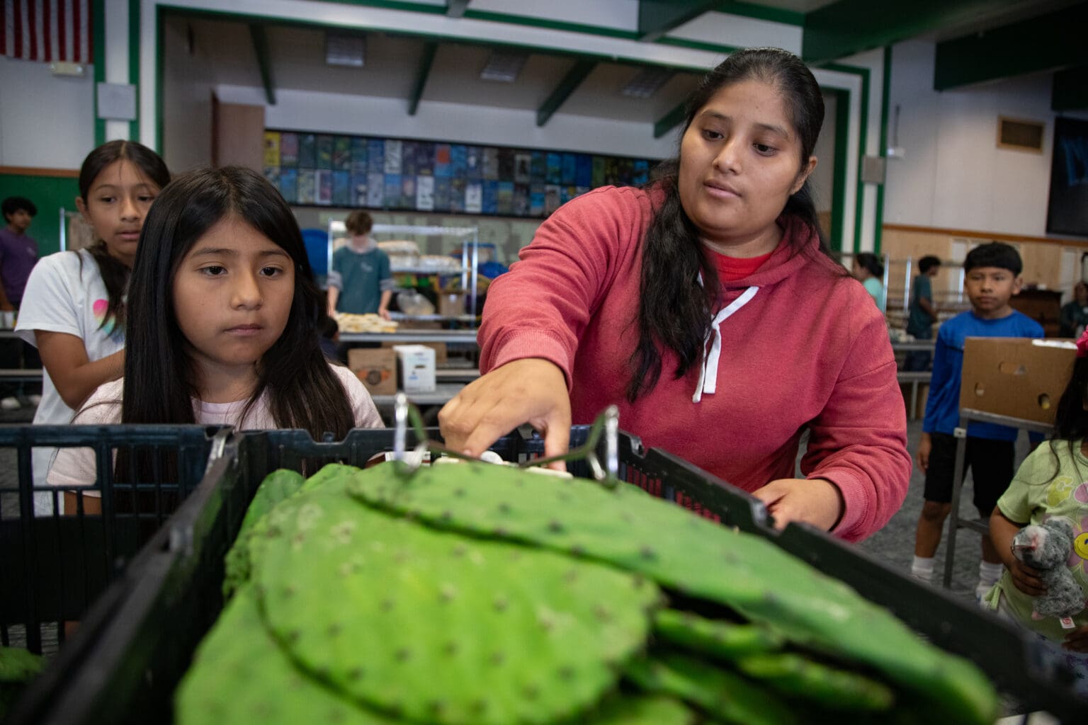 A family grabs nopal cactus leaves at the Agape Service Project's pop-up summer food bank Wednesday