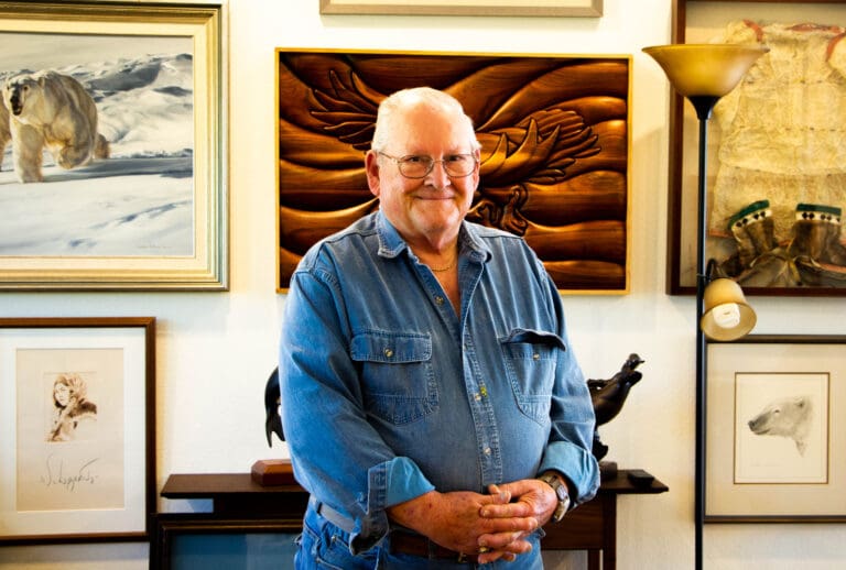Doug Hudson stands in front of his collection of artwork