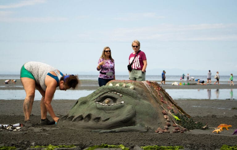 Onlookers at the Birch Bay Sand Sculpture Competition admire the prehistoric-themed sculpture July 29