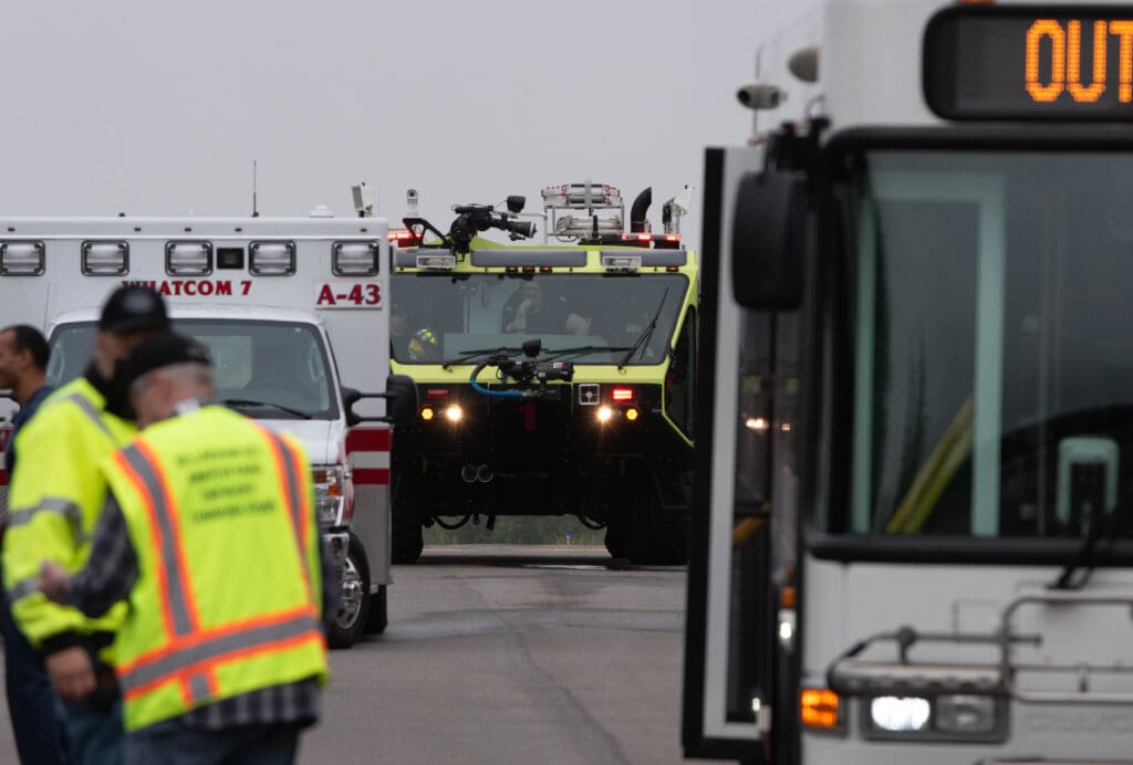 The airport's Aircraft Rescue and Firefighting truck waits behind an ambulance and WTA bus.