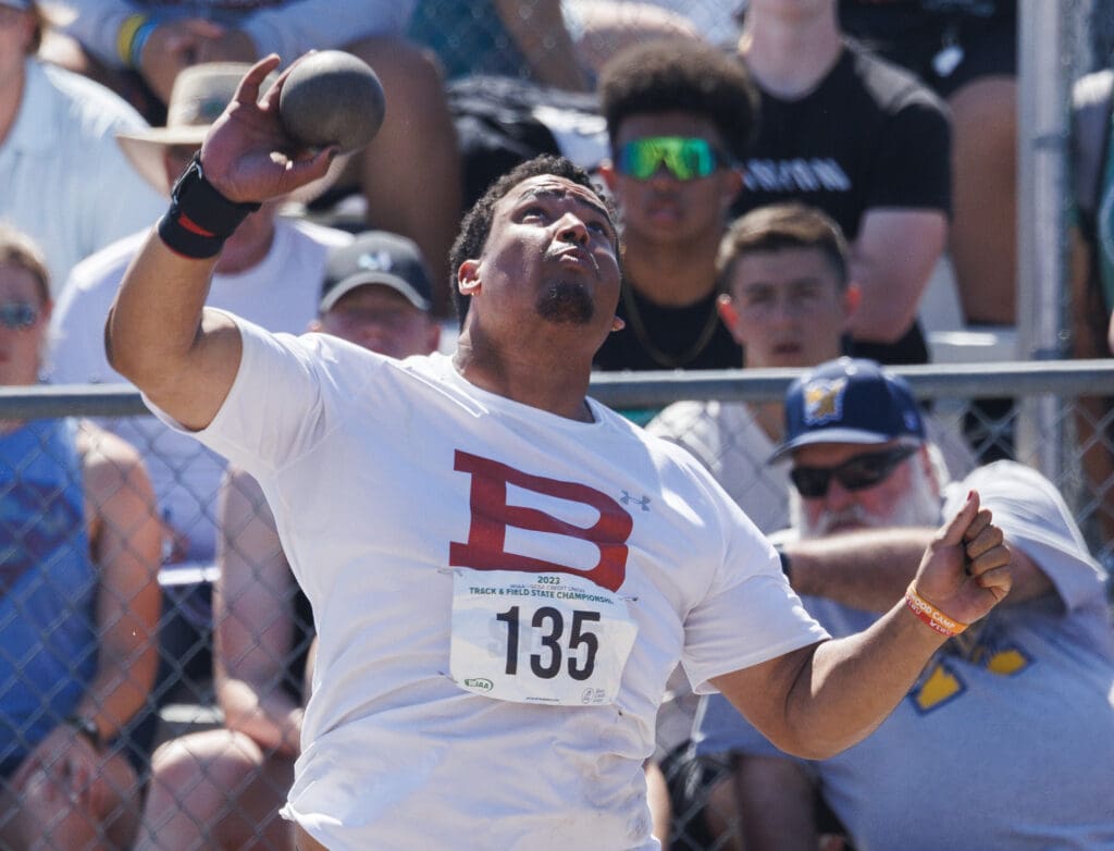 Bellingham's Javen Livas looking upwards as he gets ready to throw the shot put as spectators behind him watch.