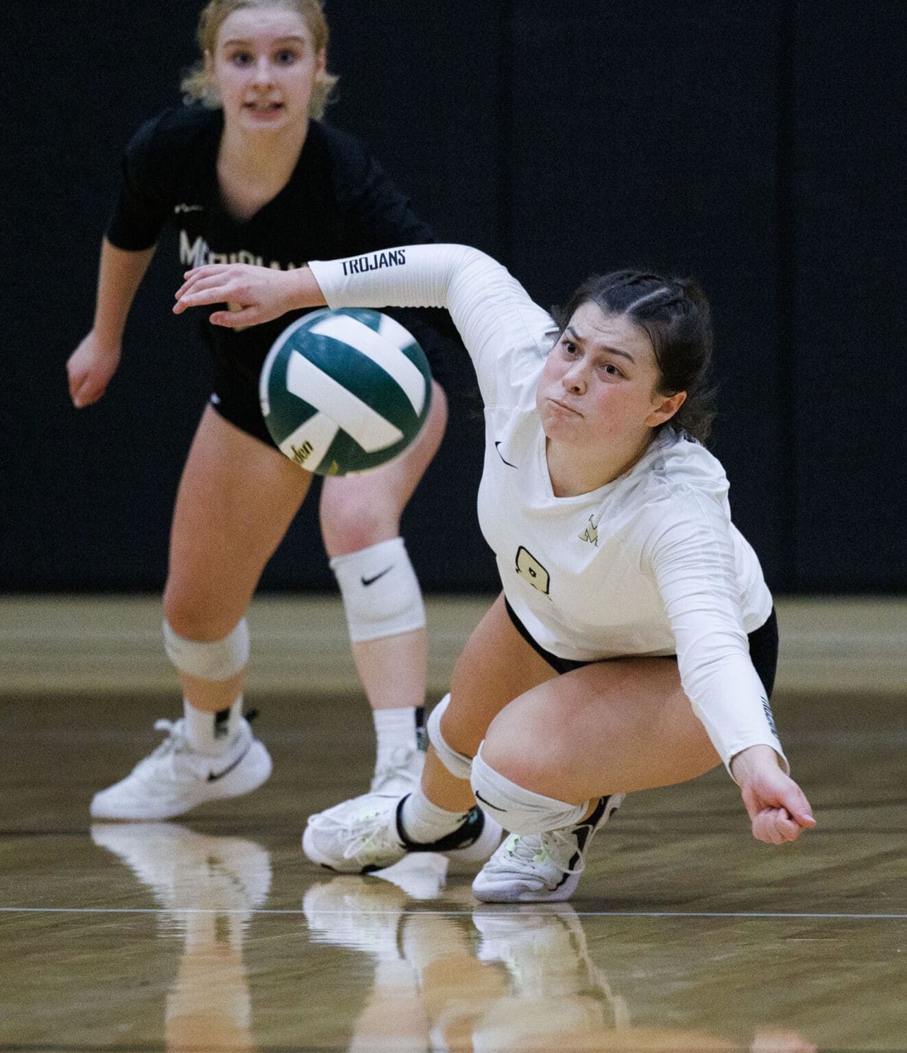 Meridian's Avery Neal dives and falls for the ball as her teammate reacts behind her.