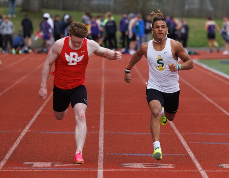 Bellingham's Hunter Dechenes and Sehome’s Andre Watson cross the finish line of their heat in the boys 100-meter dash.