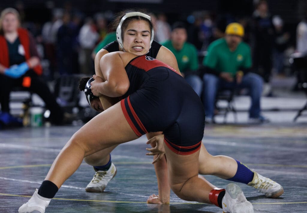 Lynden's Belen Lopez tries to gain control over Toppenish’s Ruby Rodriguez-Rios as they are in the middle of a scuffle as spectators watch from the sidelines.