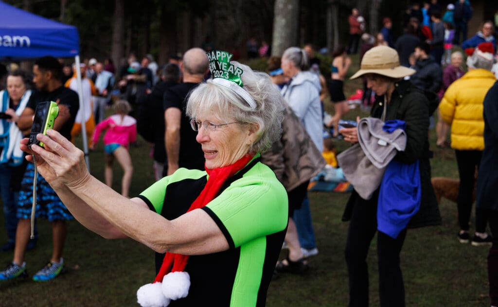Jessica Wunschel celebrates her 70th year with a selfie surrounded by other attendees as they prepare to take a dip in Lake Padden.