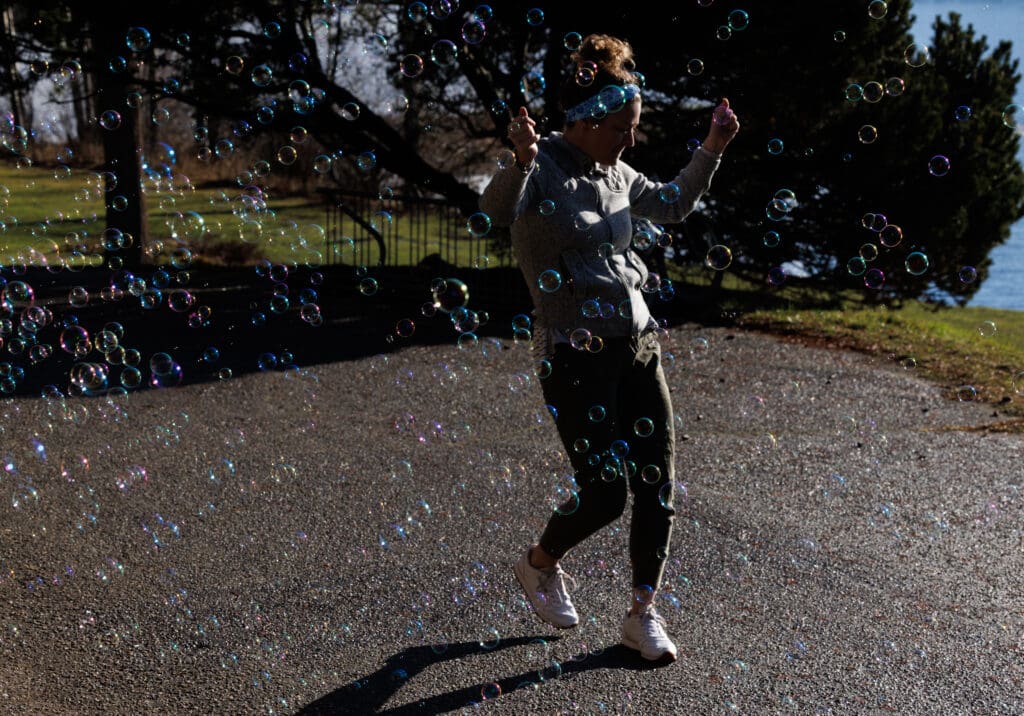Kerry Hastings in a cloud of soap bubbles as she dances on the hard gravel ground.