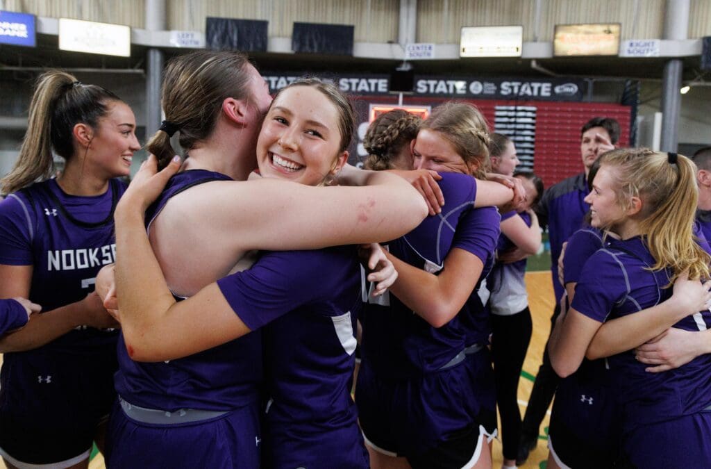 Nooksack Valley’s Devin Coppinger is all smiles as she embraces her teammates as they do the same with others in a crowded huddle.
