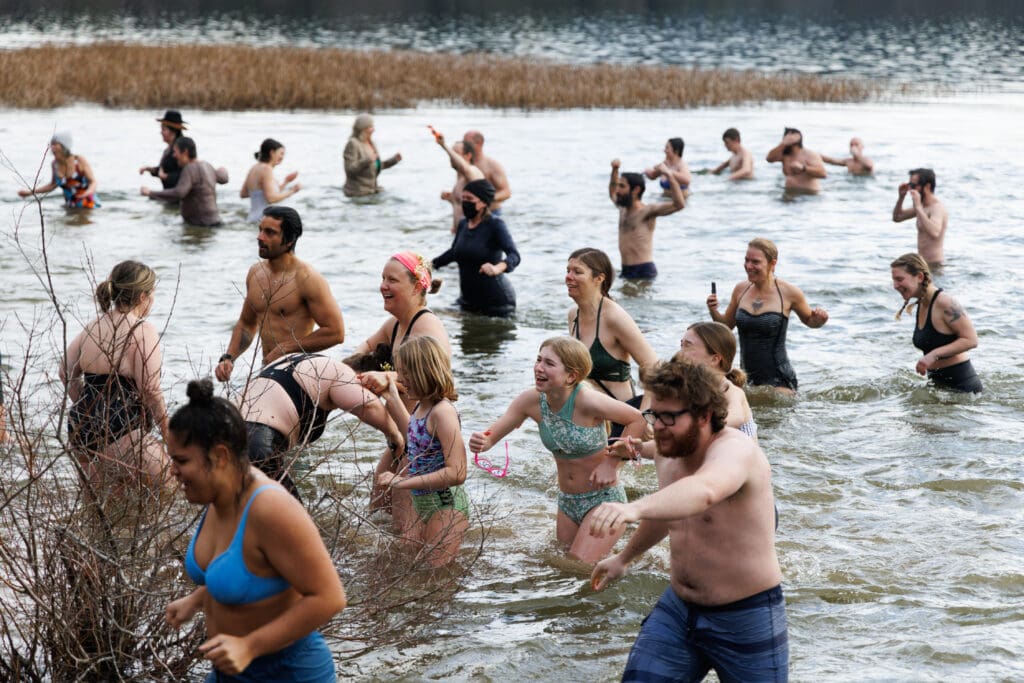 Reactions vary as people enter and exit Lake Padden's cold water with all of them dressed in swim gear.