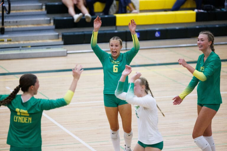 Lynden players celebrate winning as they cheer and raise their arms in celebration.