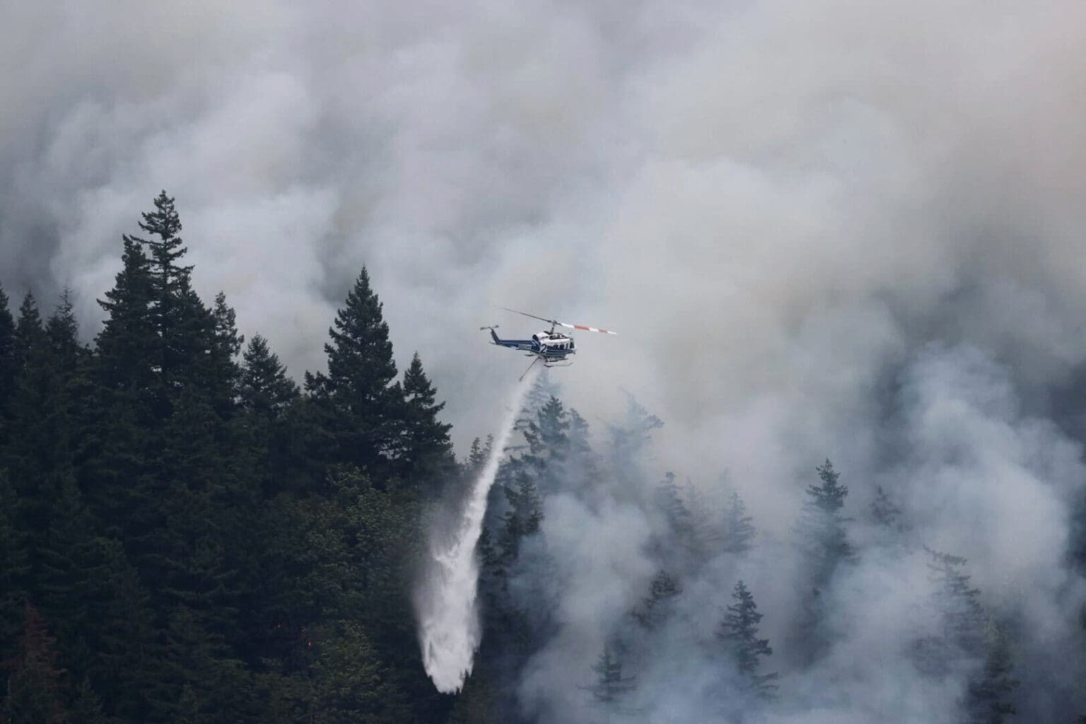 A helicopter drops water on the fire before 10 a.m. Tuesday
