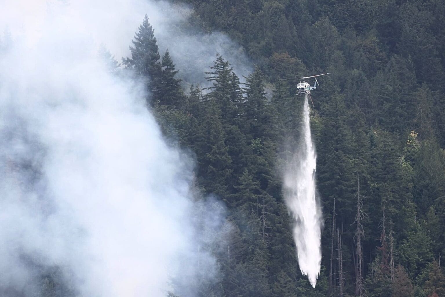 A helicopter drops water on the Lake Whatcom Fire Tuesday