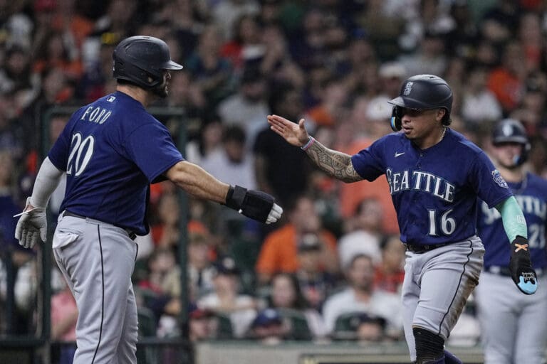 Seattle Mariners' Mike Ford (20) and Kolten Wong (16) celebrate after scoring on a single by Julio Rodriguez against the Houston Astros during the fourth inning of a baseball game Friday