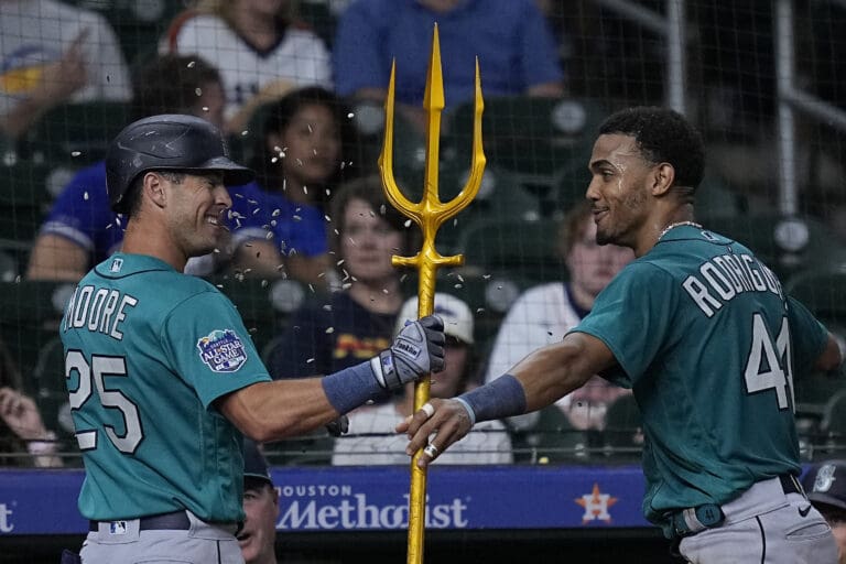 Seattle Mariners' Dylan Moore (25) is presented with a golden trident by Julio Rodriguez.