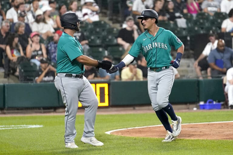 Seattle Mariners' Mike Ford, left, greets Josh Rojas with a handshake after they scored on Rojas' two-run home run off Chicago White Sox Mike Clevinger.