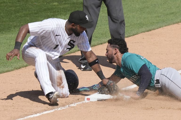 Seattle Mariners' Jose Caballero steals third as Chicago White Sox third baseman Elvis Andrus applies a late tag while dust sweeps all around them.