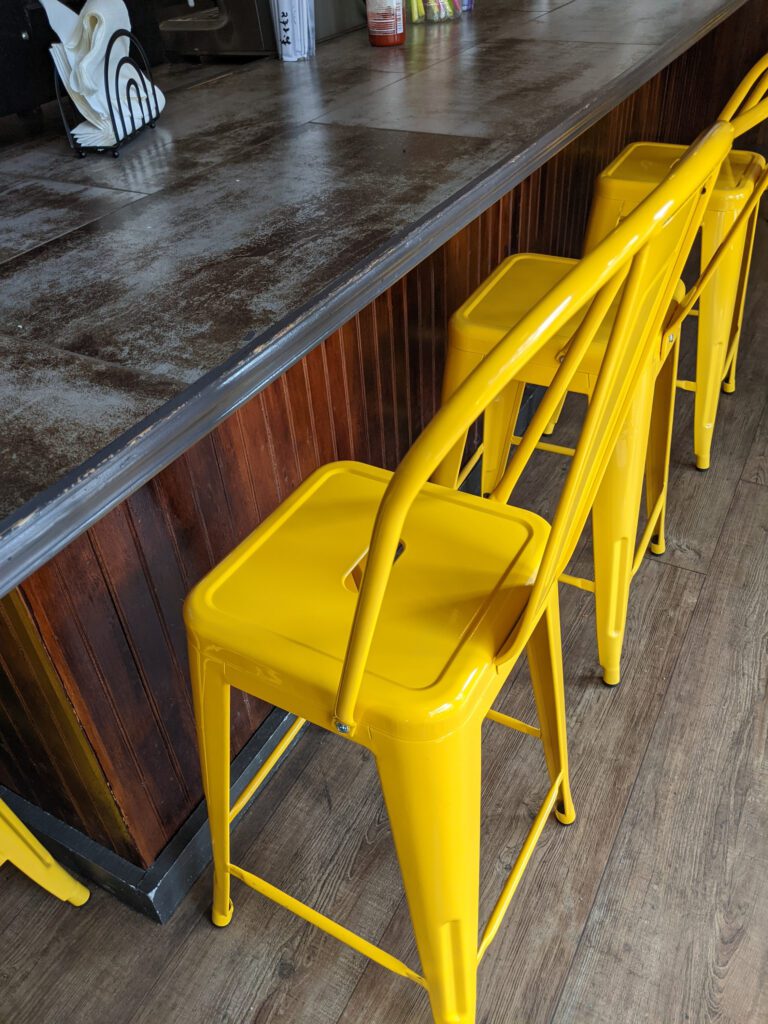Rows of yellow chairs next to the bar tables.