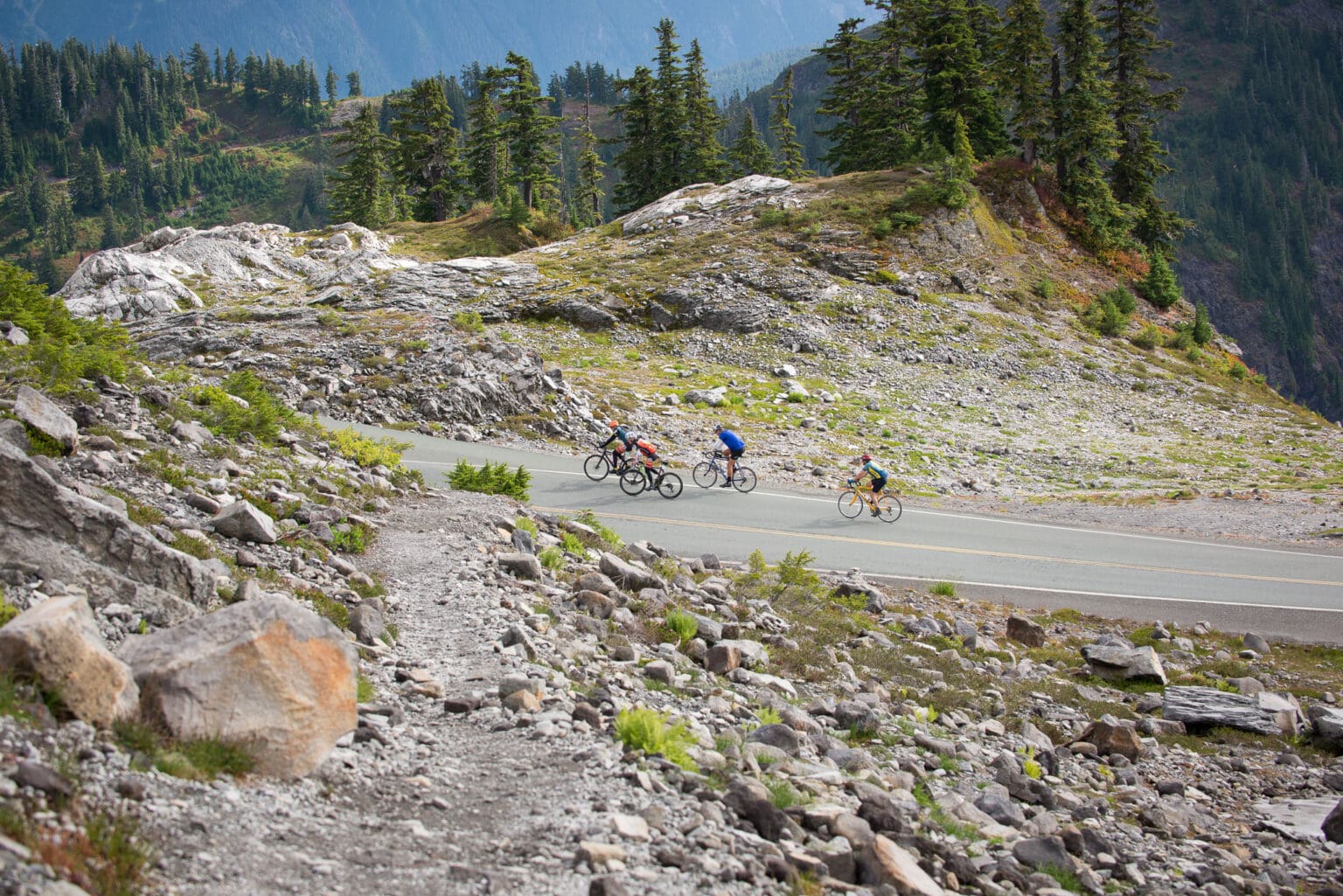 Riders push up Mount Baker Highway surrounded by rocks.