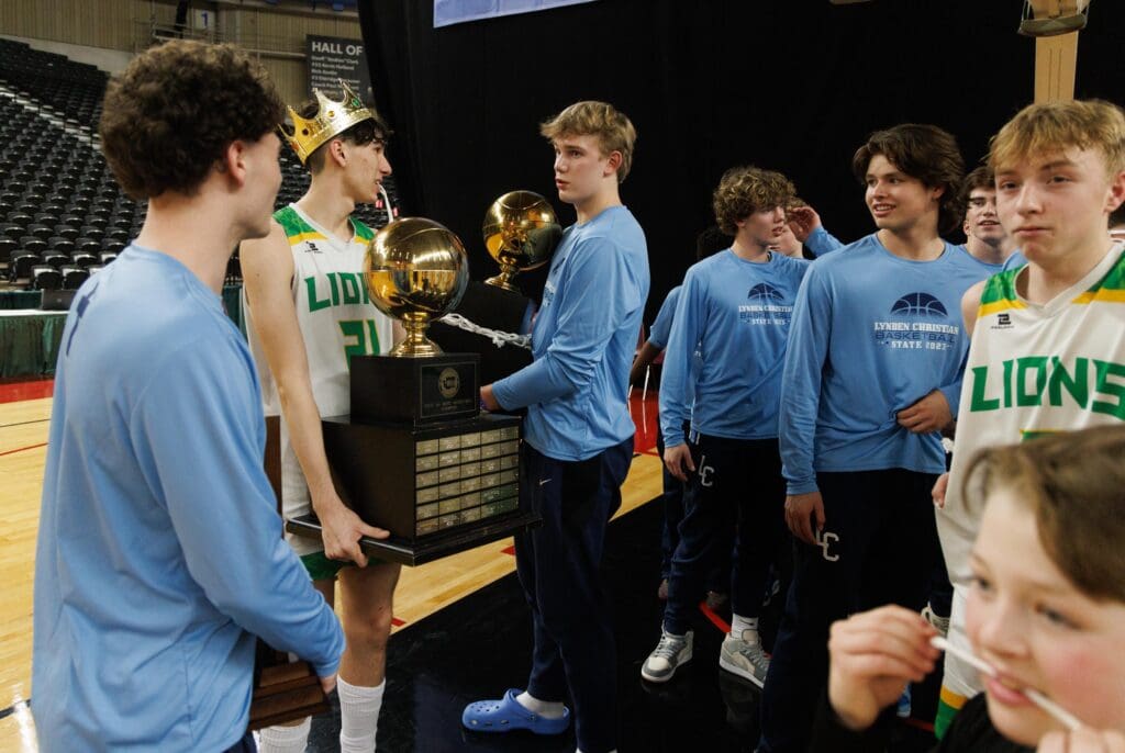 Lynden’s Anthony Canales and Lynden Christian's Jeremiah Wright chat while one of them holds the trophy with a crown on his head.
