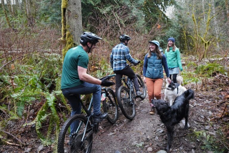 Mountain bikers Jeff Bowers and Henry Lawrence stop along a narrow path of the Y Road Trail to chat with dog walkers Sarah Finger and Michelle Cousins