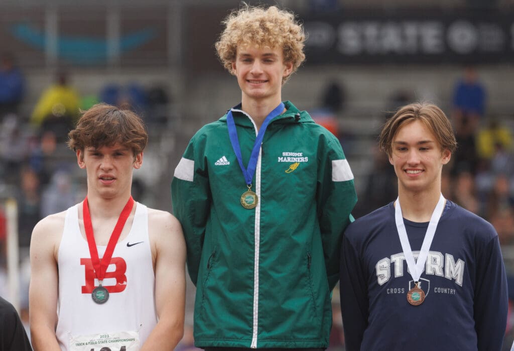 Sehome's Zack Munson, middle, is joined by Bellingham's William Giesen, left, and Squalicum's Chase Bartlett on the podium as they smile for the camera with their medals.