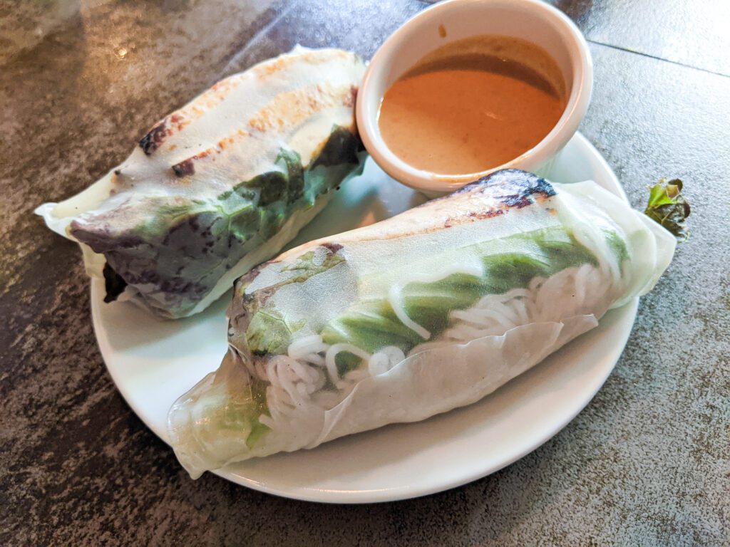 Fresh rolls served on a plate with a side of sauce.