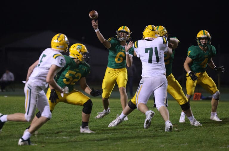 Lynden’s Brant Heppner throws a touchdown pass as his teammates block other players from reaching him.