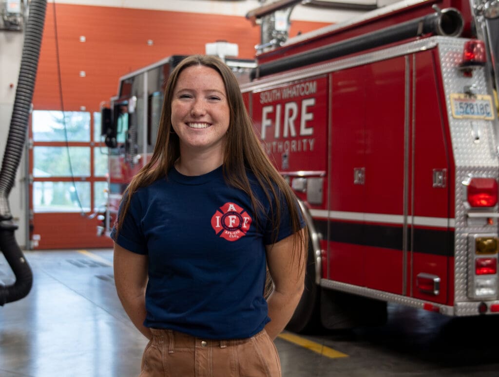 Austyn Brown smiles as she poses for a photo next to a firetruck.